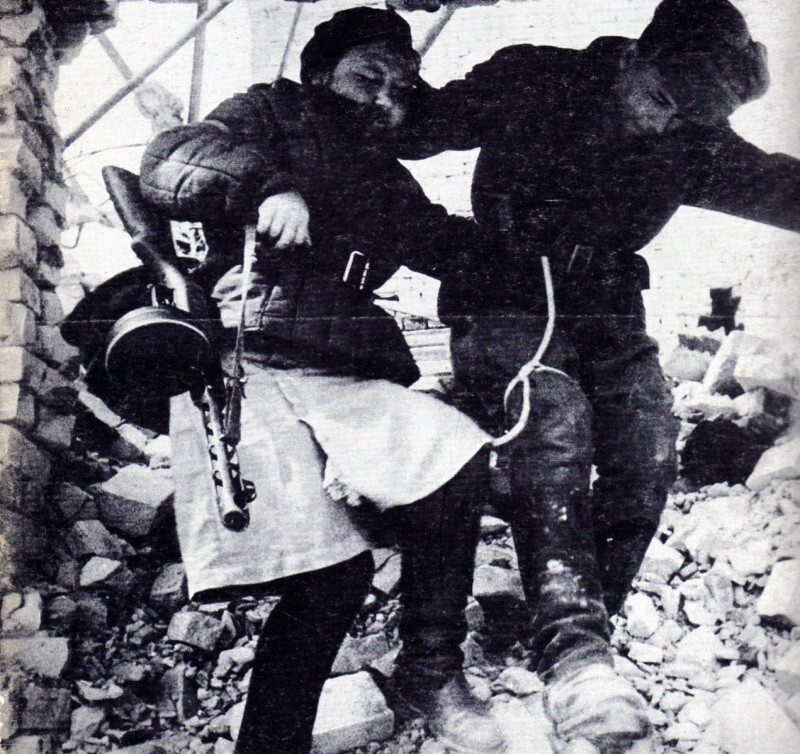 Девушка-санинструктор сопровождает раненого солдата в Сталинграде.
