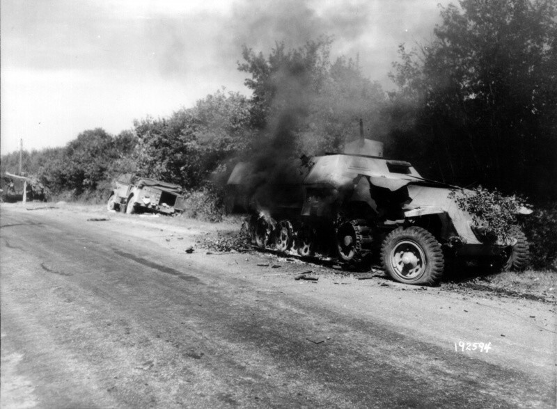 Горящая немецкая техника (бронетранспортер) на дороге около деревни Сен Обин-д'Аппена (St Aubin-d'Appenai) на дороге между Алансоном (Alencon) и Мортанью (Mortagne) в Нормандии.