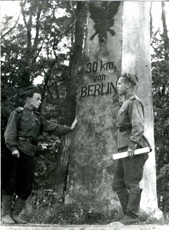 Двое советских военнослужащих у указателя «30 километров до Берлина».