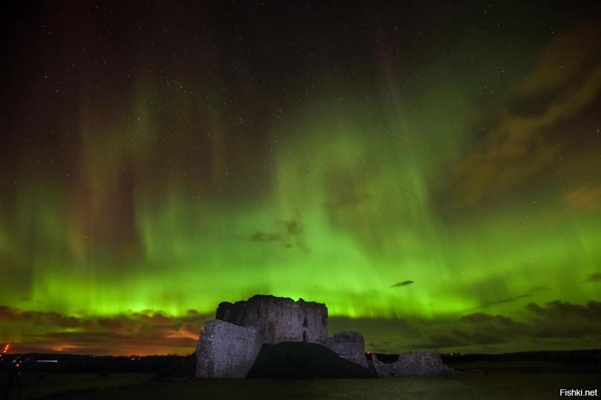 Захватывающее Северное полярное сияние освещает ночное небо над руинами замка...