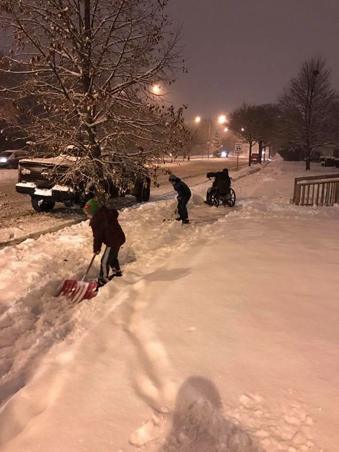 24. Дети, помогающие мужчине на коляске убирать снег