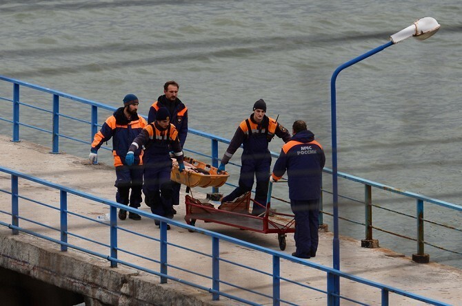 Спасатели несут тело погибшего в крушении самолета Минобороны РФ Ту-154 у побережья Черного моря в Сочи. 