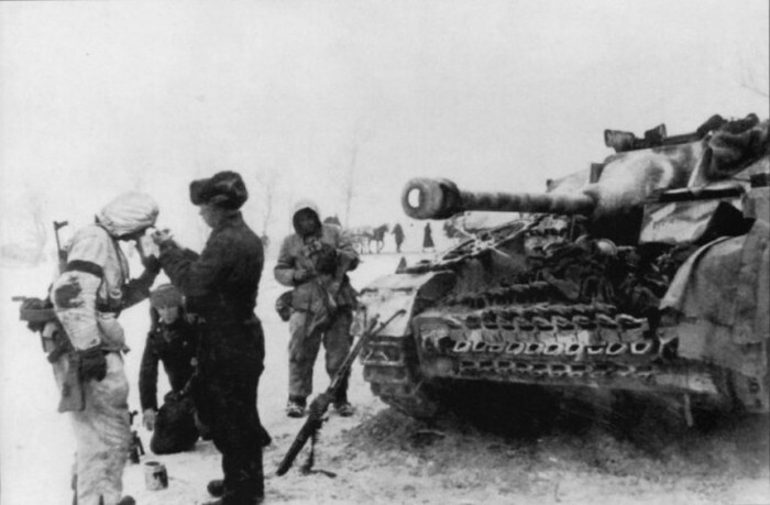 Немецкий солдат, вооруженный штурмовой винтовкой StG 44 прикуривает у самоходчика из экипажа штурмового орудия StuG IV.