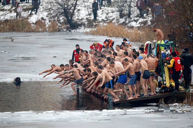 В Болгарии, София священник бросает в воду деревянный крест (летит слева). Цель — первыми отыскать его в воде. 