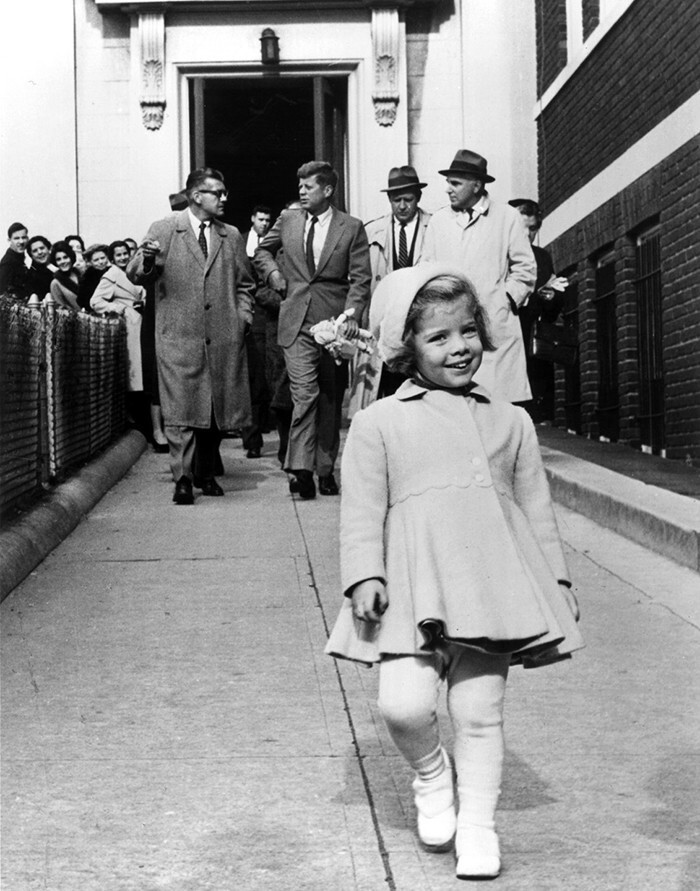 Кэролайн Кеннеди на переднем плане, отец несёт её куклу сзади, 1963