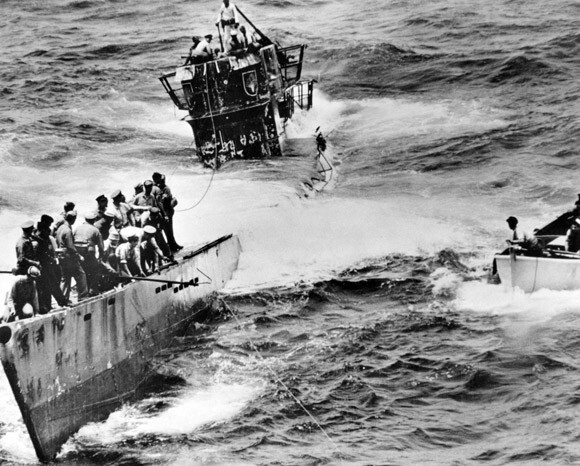 На палубе лодки полно американских матросов, они готовятся к буксировке захваченной немецкой подлодки U-505 в порт на Бермудских островах июнь 1944 года. (Фото: US Navy)