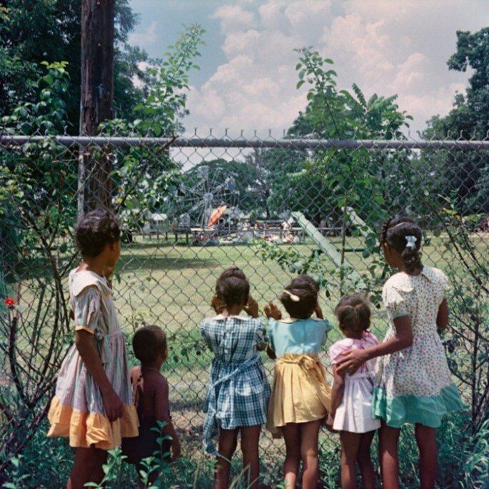 Темнокожие дети наблюдают за белыми ребятишками, играющими в парке