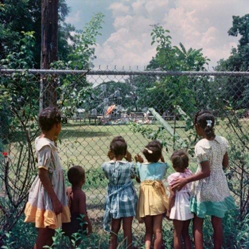 Темнокожие дети наблюдают за белыми детьми, играющими в парке, 1956 год.