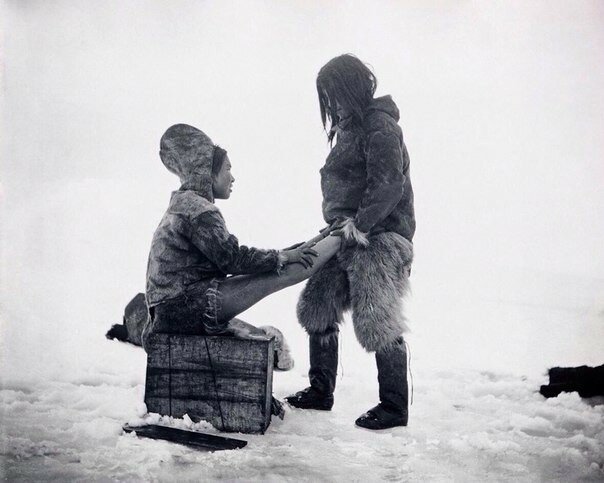 Мужчина-инуит согревает ноги жены. Гренландия, 1880-1890-е