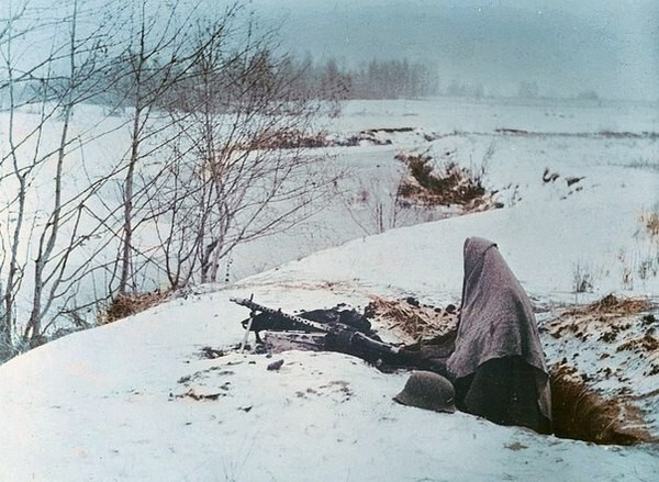 Укутанный в одеяло солдат вермахта у 7,92-мм пулемета MG-34 в окопе на берегу реки на Восточном фронте.