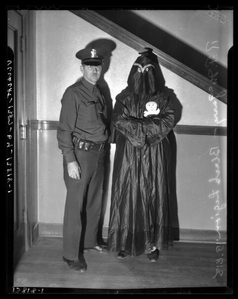 Полицейский стоит рядом с членом «Черного легиона»