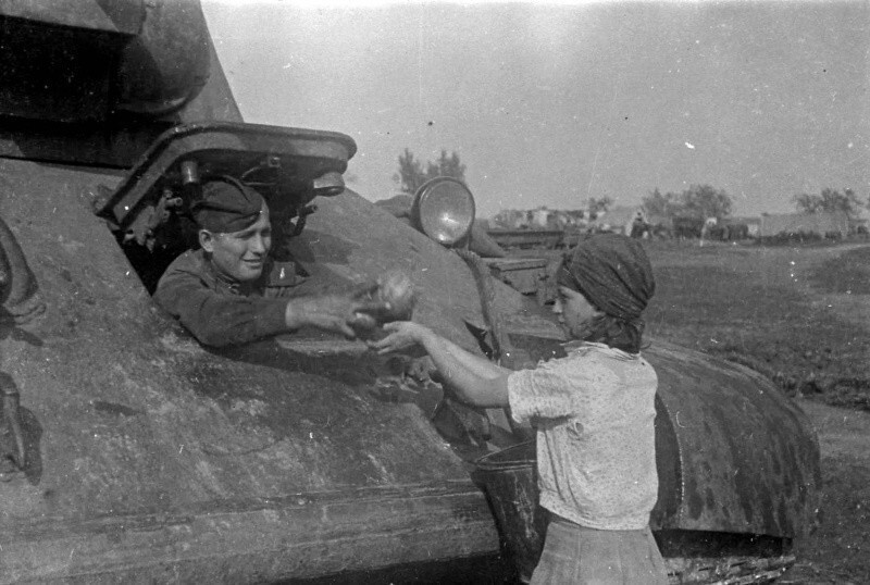 11. Жительница освобожденного украинского села угощает арбузами механика-водителя танка Т-34. 1943.