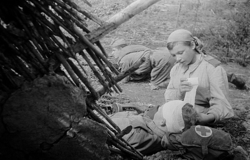 14. Санинструктор 705-го стрелкового полка старший сержант В.А. Пономарева перевязывает раненого в голову младшего лейтенанта Н.С. Смирнова. 1943.