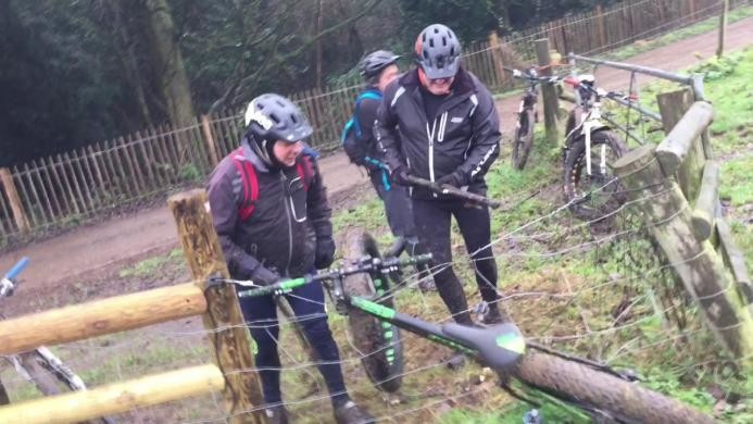 Трое мужчин пытаются вытащить велосипед, застрявший в электрическом заборе 