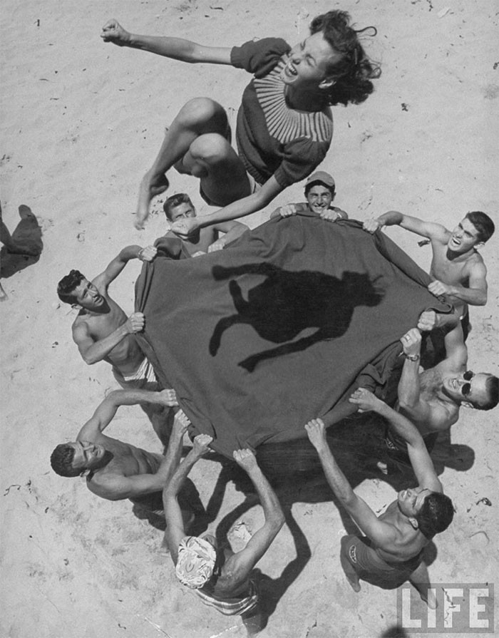28. Парни подбрасывают свою подругу Норму Бейкер в воздух на пляже, 1948 г.