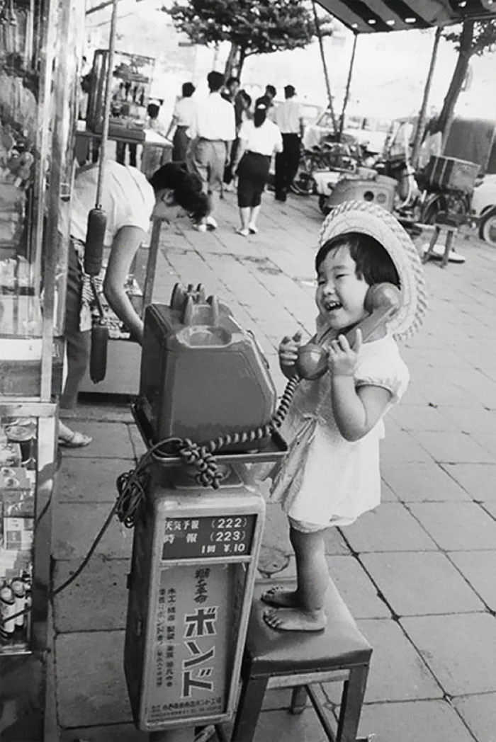 19. Девочка веселится, изображая разговор по телефону. Япония, 1958 г.