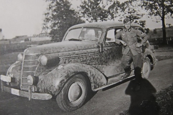 Солдат Вермахта позирует у трофейного автомобиля "Chevrolet" 1938 года выпуска.