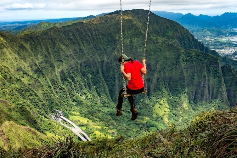 11. Женщина, которая качается на горной вершине после восхождения на Лестницу Хайку в Oʻahu, Гавайи.