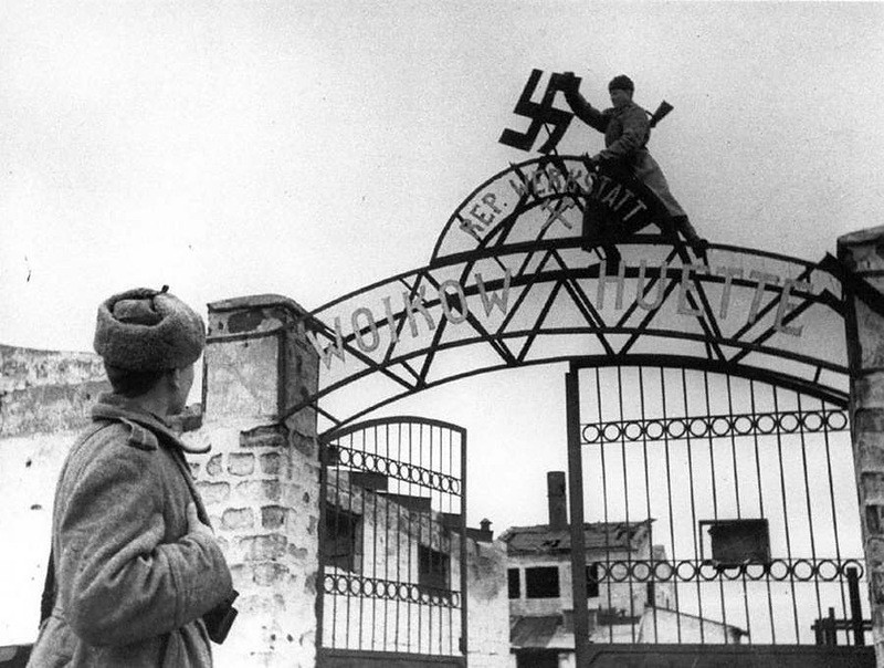 Советские бойцы сбивают фашистскую свастику с входа на территорию завода им.Войкова в освобожденном городе Керчи, 1944.