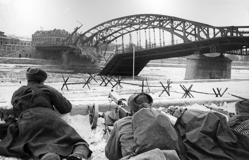Советские бойцы с пулемётом «Максим» ведут огонь у разрушенного моста через реку Висла в боях за освобождение Кракова, январь-февраль 1945 года.