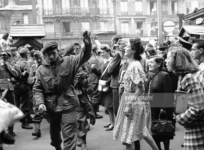 Парижане оплевывают пленных британских парашютистов, которых немцы ведут по городу.