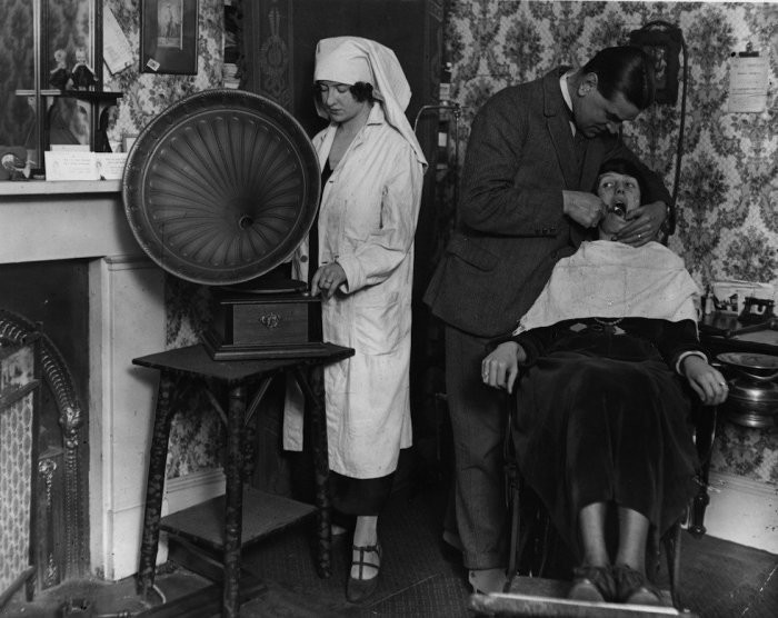 Помощница стоматолога включает радио на полную громкость, чтобы отвлечь пациента от боли. 1922 год.