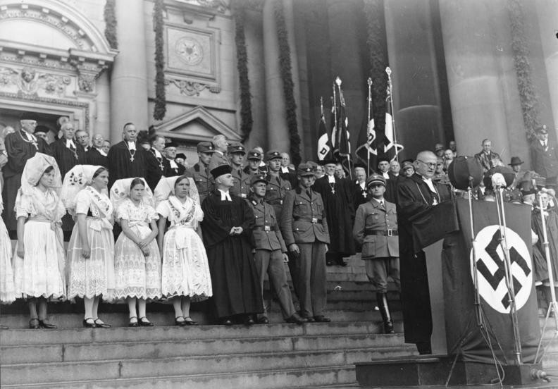 21. Рейхс-епископ Людвиг Мюллер произносит речь в Берлинском соборе с кафедры, обернутой в нацистский флаг, сентябрь 1934 г