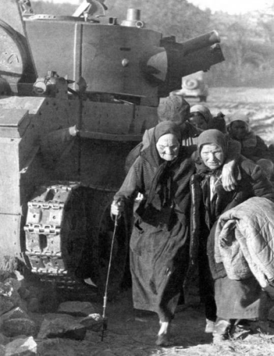 Беженцы идут мимо подбитого танка БТ-7А, июнь 1941.