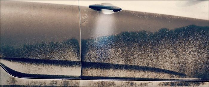 Разводы на грязной по ручку дверце машины напоминают летающую тарелку, зависшую над лесом