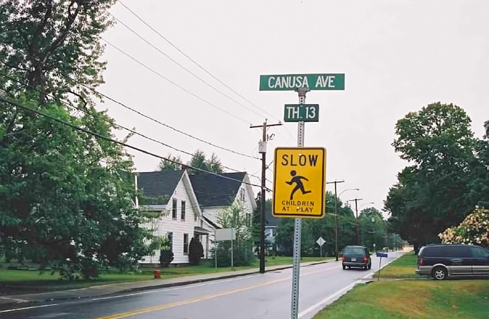 По одну сторону забора - зеленые указатели улиц, канадские ...