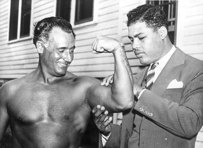 Чемпион мира в сверхтяжелом весе по боксу Джо Луис , восхищается бицепсу Чарли Атласа (Charles Atlas), который считался на то время самым накаченным человеком в мире, 1938 год.