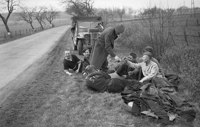 53 Британский солдат угощает сигаретами освобожденных советских военнопленных на дороге к северу от Ганновера. 1945г.