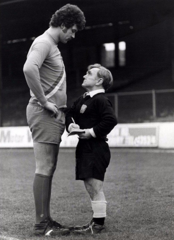Футбольный арбитр Джоуи Шаклфорд (рост 1,46 м) выносит предупреждение игроку Клайву Годдарду (рост 2,06 м). Англия, 1980 год.