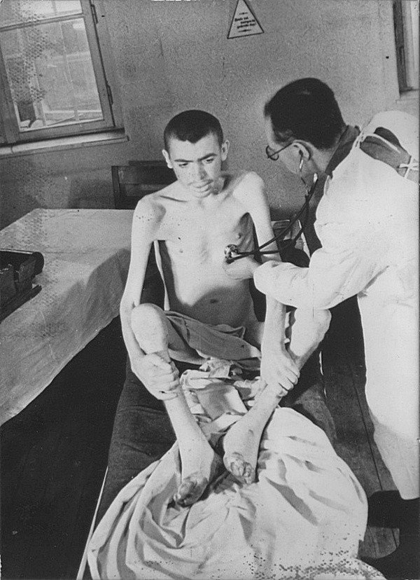 Врач из состава советской врачебной комиссии осматривает освобожденного узника концлагеря Освенцим.