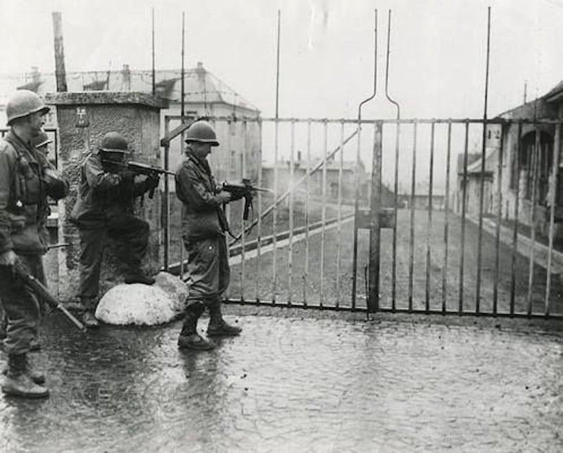 Американские солдаты расстреливают замки ворот немецкого лагеря военнопленных в Хаммельбурге. 6 апреля 1945 года.