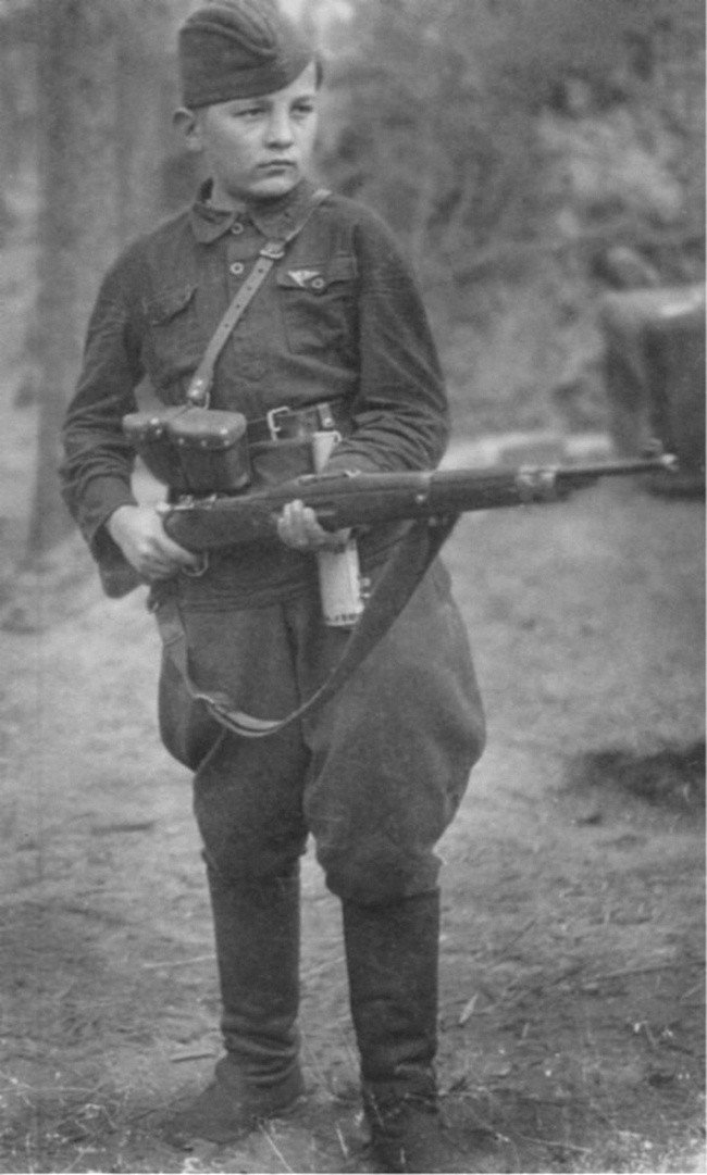 13-летний разведчик-партизан Федя Мощев. Авторская аннотация к фото — «Мальчику нашли немецкую винтовку».  Время съемки: октябрь 1942