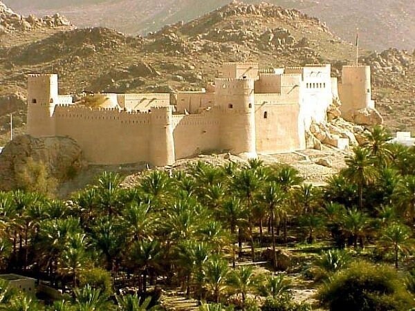 16. Форт Nakhl находится с видом роскошной зелени финиковых пальм оазиса в Омане.