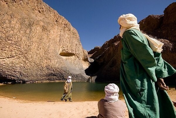 8. Это потрясающее изображение показывает трех мужчин для утоления жажды в небольшой водопад в оазисе Сахары Timia, в Нигере.