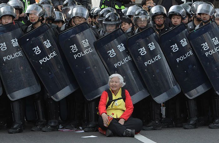 Кореянка блокирует путь спецподразделению полиции для защиты протестующих во время демонстрации против политики правительства. Сеул, Южная Корея, 2015 год