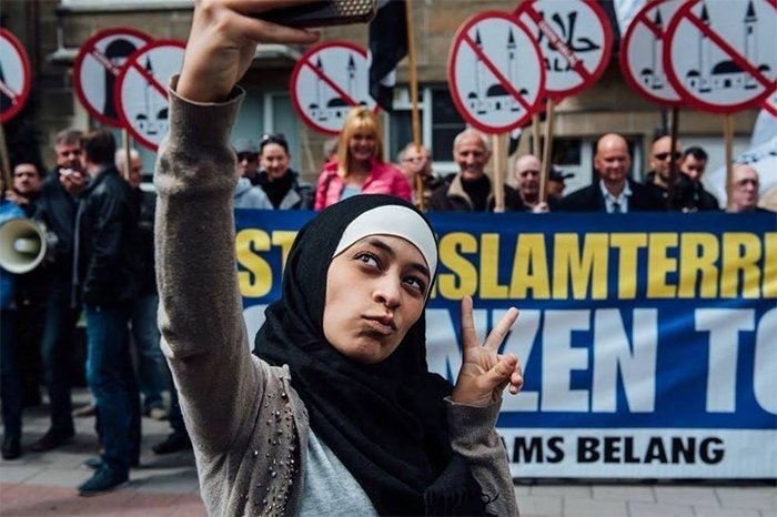 Мусульманка делает селфи на фоне антимусульманской демонстрации в Антверпене, Бельгия, 2016