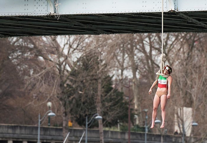 Активистка Сара Константин висит на веревке на мосту, чтобы привлечь внимание к большому количеству казней в Иране. Париж, 2016