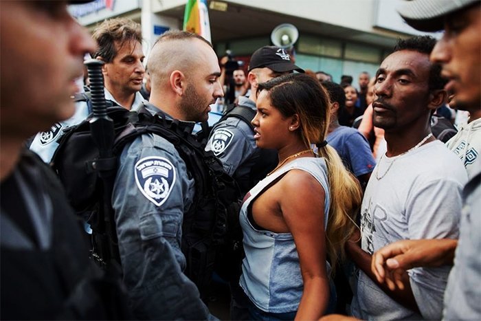 Девушка и полицейский во время акции протеста в Тель-Авиве против жестокости полиции