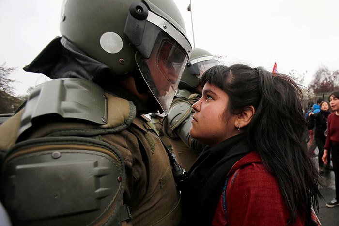 Лицом к лицу: девочка-демонстрант и полицейский на акции протеста в честь годовщины военного переворота 1973 года в Сантьяго, Чили