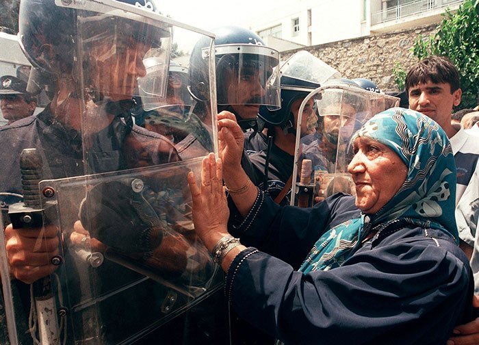 Пожилая женщина пытается сдерживать полицейских на митинге за культуру и демократию, Алжир, 2011