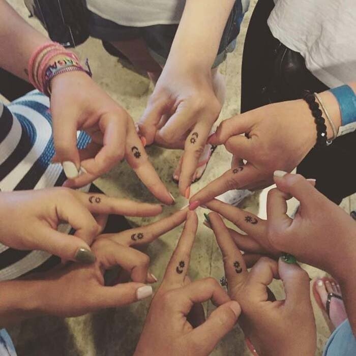 Восемь девчонок, чтобы показать свою связь, нанесли на свои пальцы крошечные татуировки луны и солнца