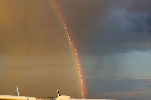 Молния попадает в самолет на фоне радуги