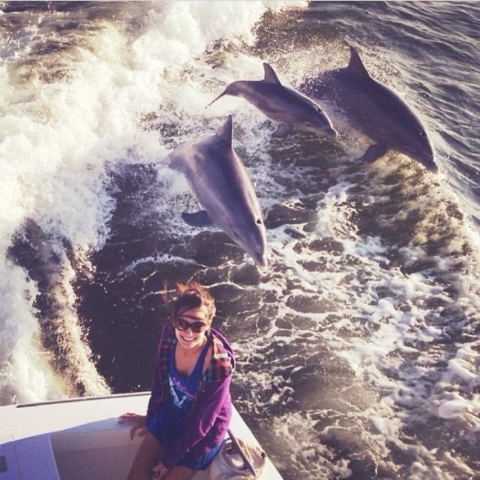 4. "Плавали мы на лодке, я позировала для фотографии - и тут позади меня три дельфина как выпрыгнут из воды! Удачный снимок получился"