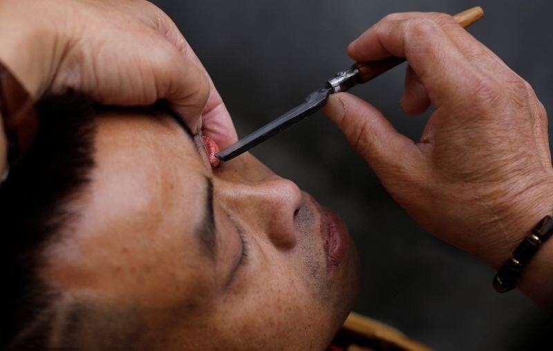 Уличный парикмахер в Китае чистит глаза клиентам опасной бритвой