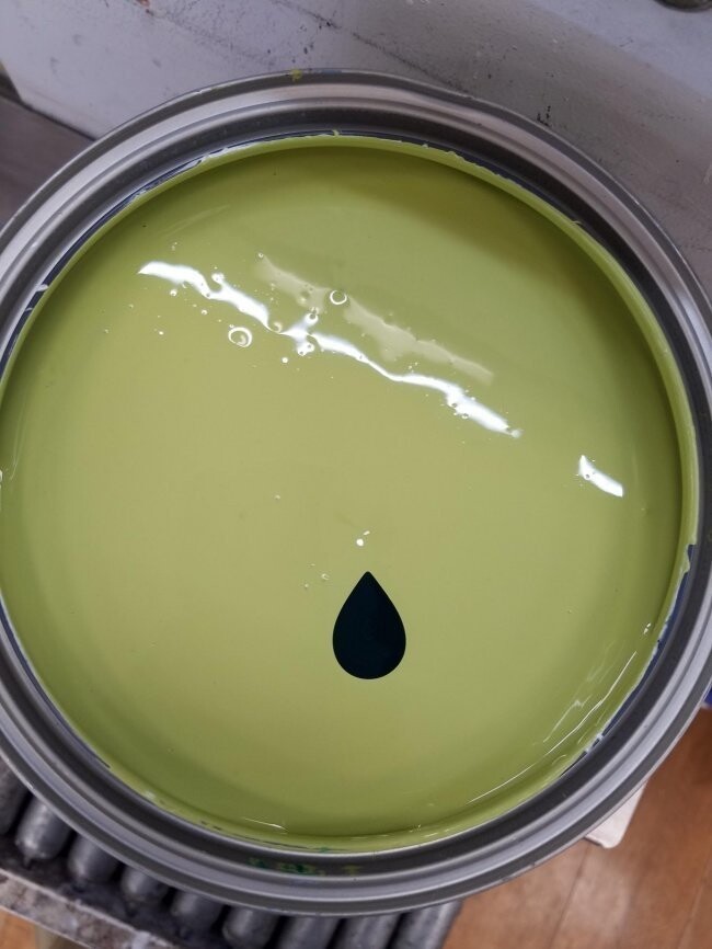 Совершенная капля темно-зеленой краски в банке со светлой краской