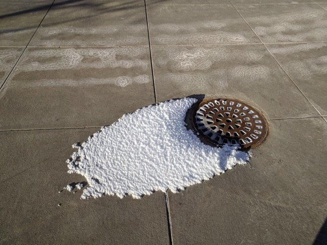 Пар из канализационной решетки превратился в снег из-за мороза.